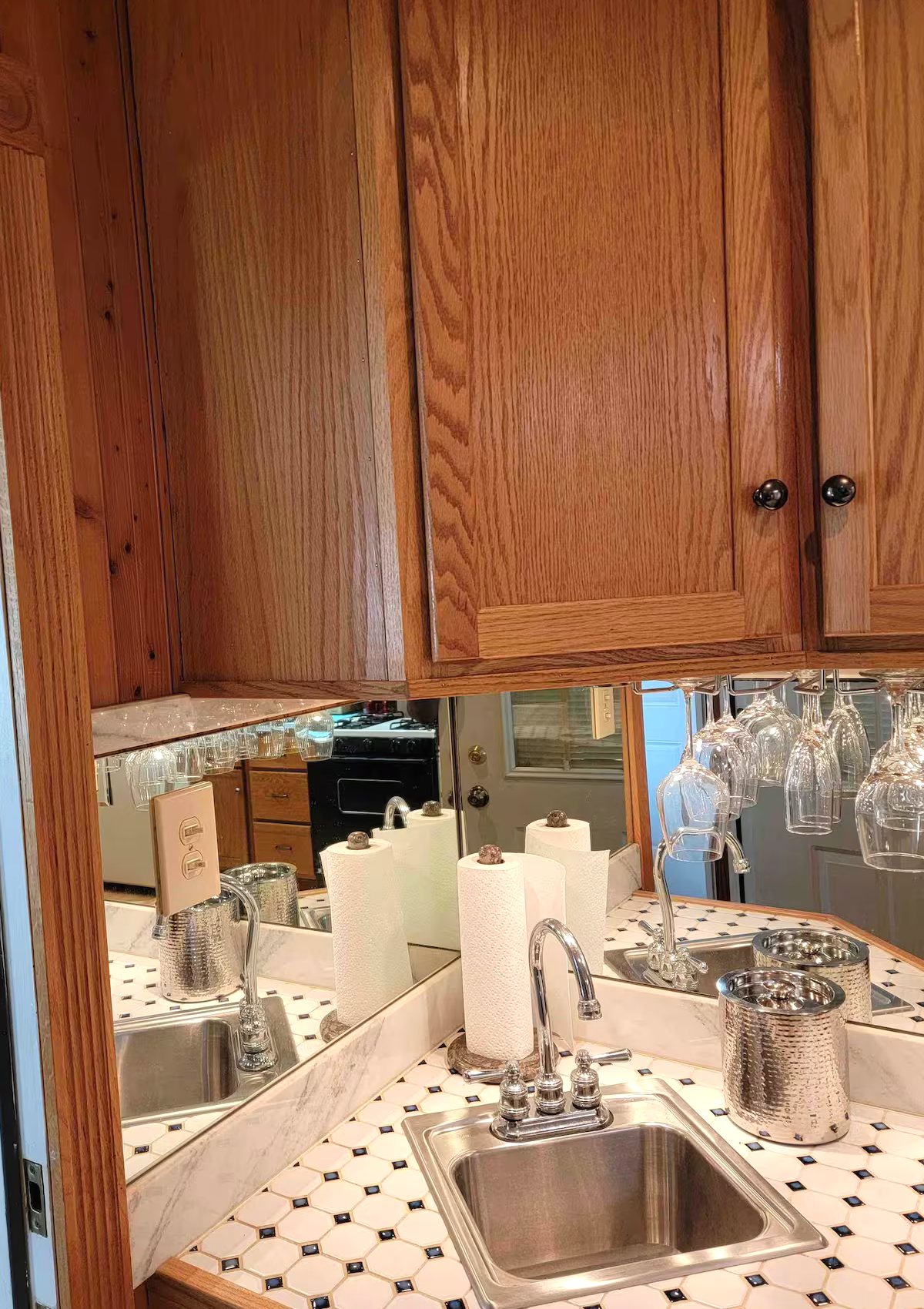 Wet bar with mirrored backsplash, sink, and glassware